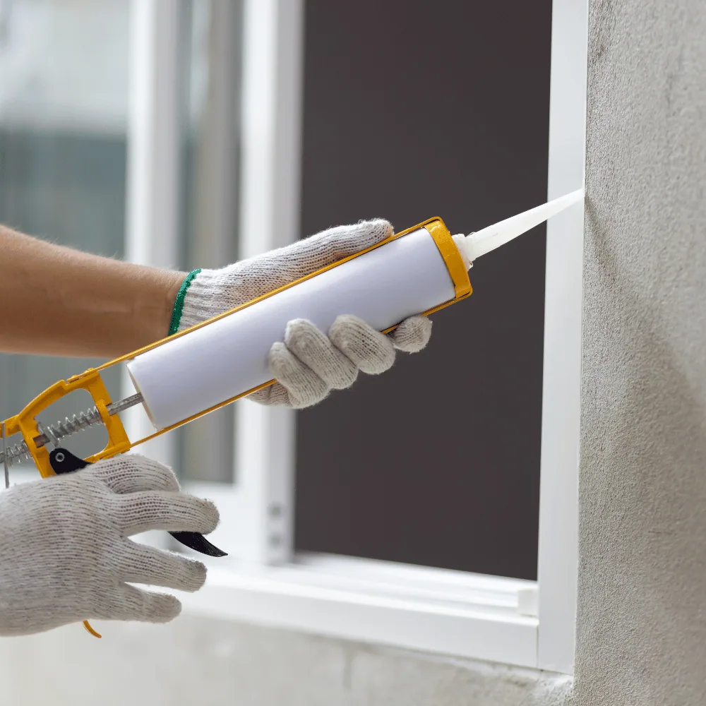 Caulking around a window frame to keep ladybugs out of the house